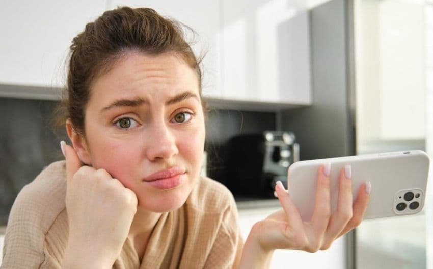 Сумна жінка тримає телефон у руці Сумна жінка тримає телефон у руці