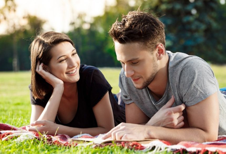 Друзі спілкуються, лежачи на покривалі в парку