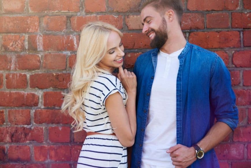 Девушка красиво отвечает на флиртовой вопрос парня стоя у керпичной стены Девушка красиво отвечает на флиртовой вопрос парня стоя у керпичной стены